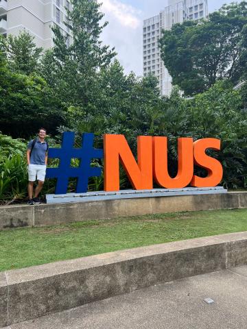 Nicolas beside the NUS sign at University Town